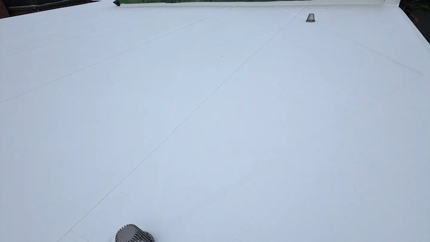 New white TPO membrane on a flat roof with a drain, installed by RC All Exteriors