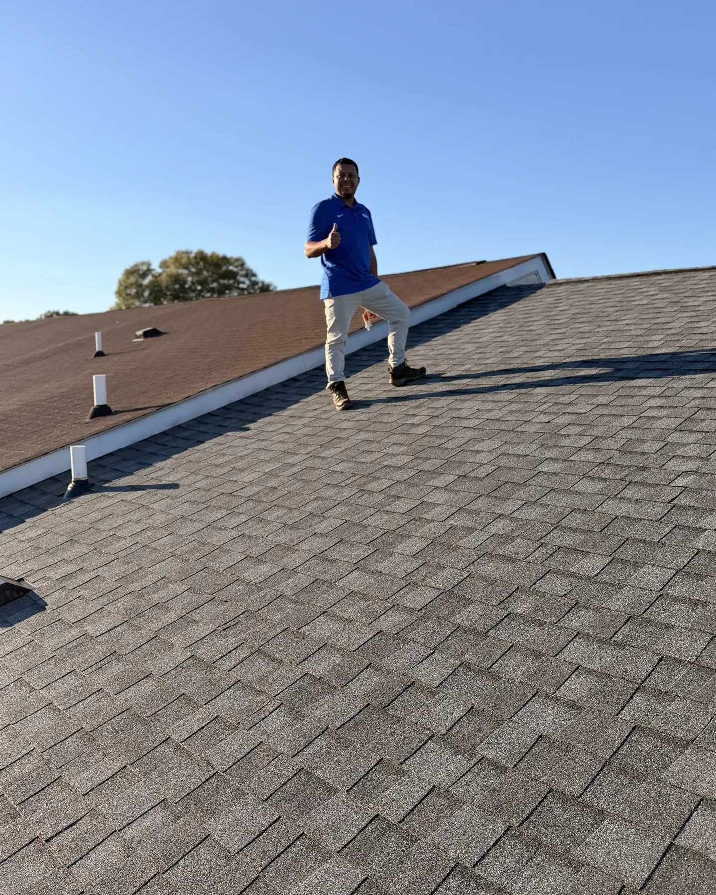 An RC All Exteriors professional walking a shingle roof during an inspection