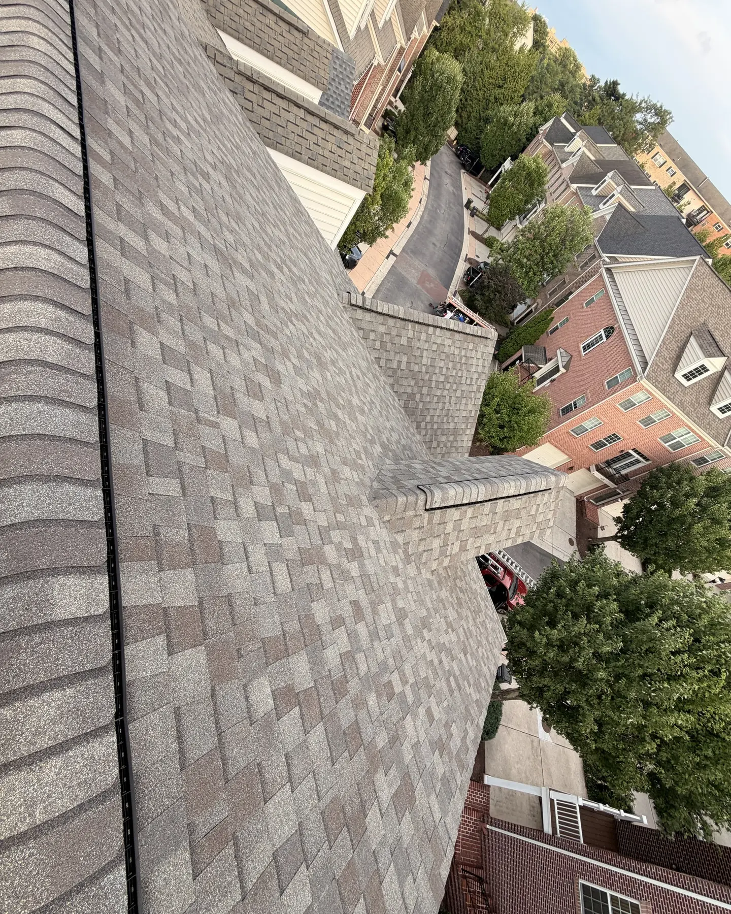 New tan architectural shingle roof on a brick townhouse, looking down the ridge