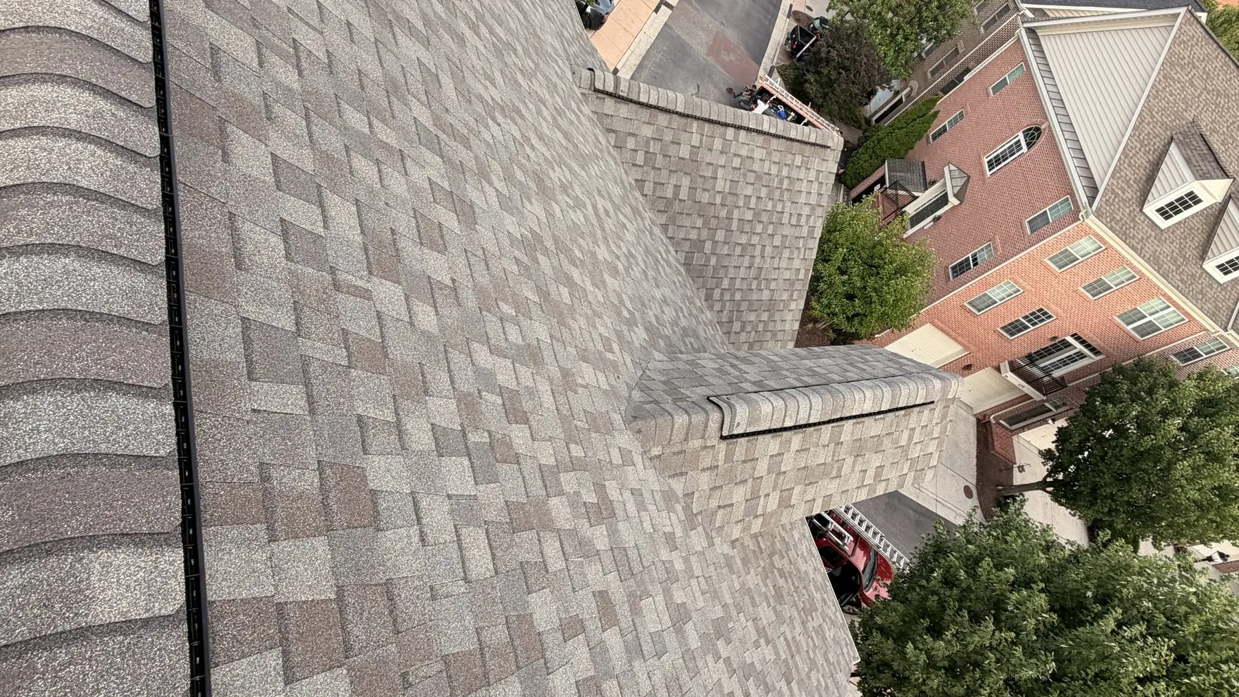 New tan architectural shingle roof on a brick townhouse, looking down the ridge