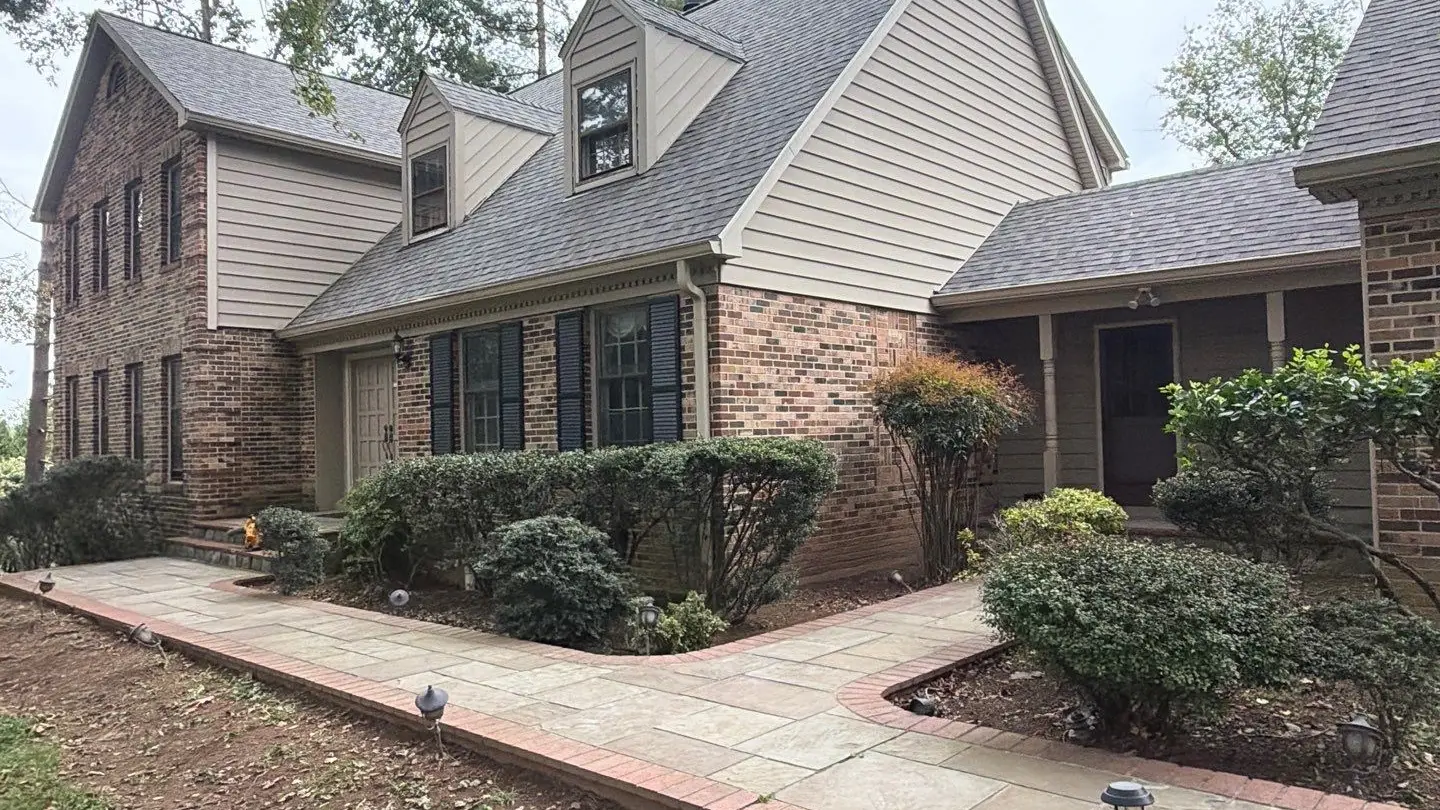 Front walkway of a brick two-story home with a new gray shingle roof