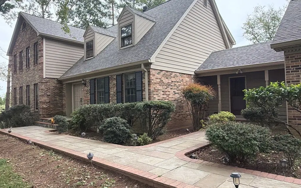 Front walkway of a brick two-story home with a new gray shingle roof