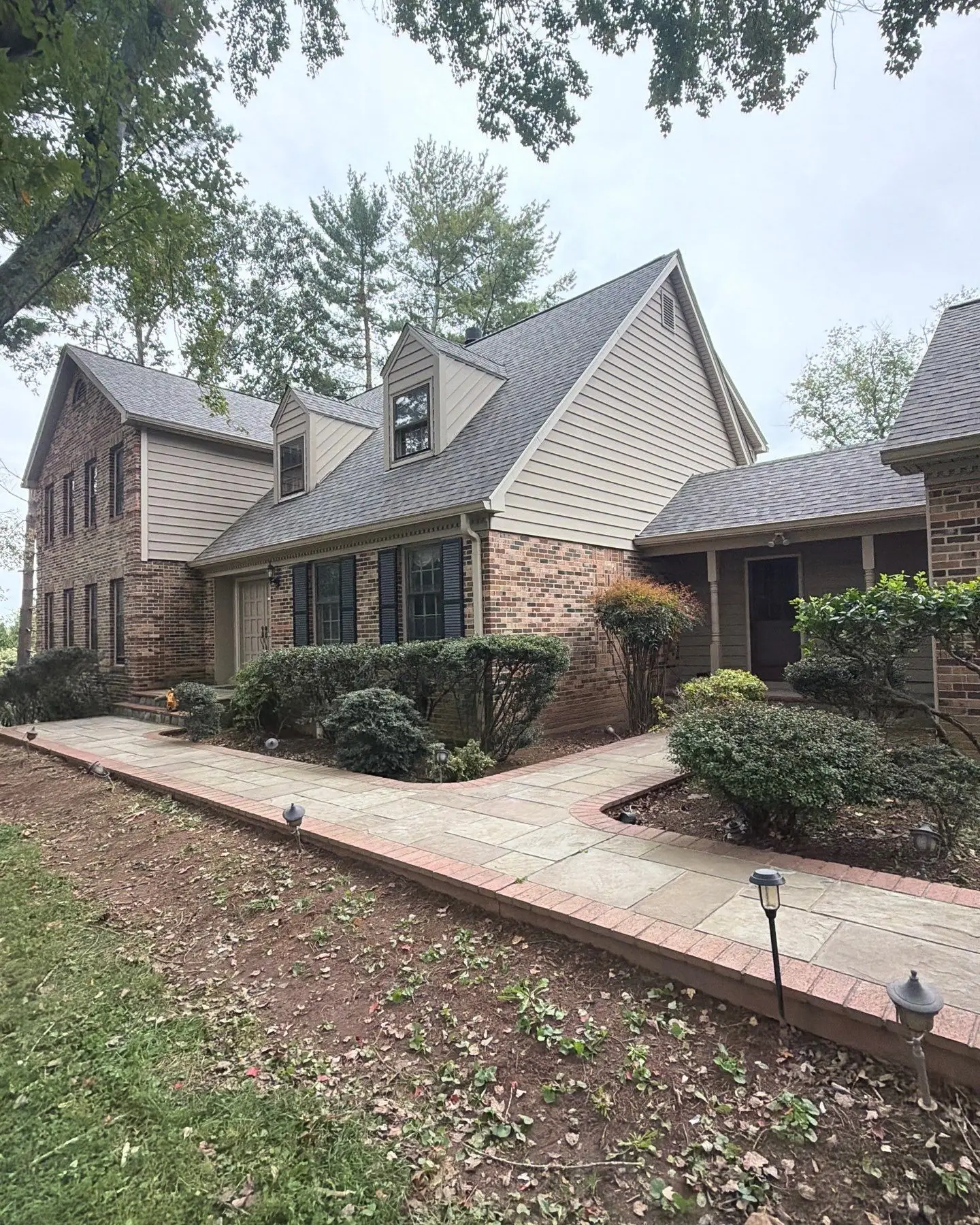Front walkway of a brick two-story home with a new gray shingle roof